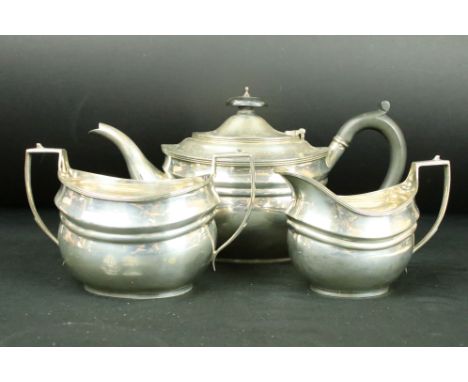 Three piece silver tea service, moulded design with two engraved crests, reeded angular handles and border, the teapot with e