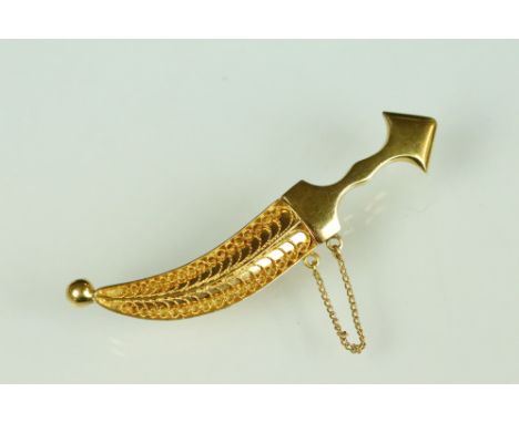 Yellow metal brooch modelled as a sabre with filigree scabbard, hinged pin and simple loop brooch fittings, safety chain, len