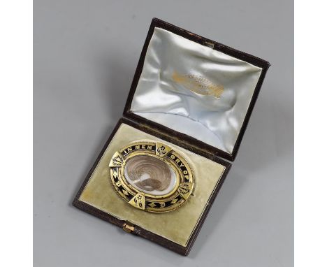 A Victorian yellow metal and black enamel oval memorial brooch, in original box, with plaited hair and inscribed verso 'Peter