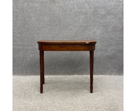A George III crossbanded mahogany foldover demi lune card table with a baize lined top on square tapering supports with spade
