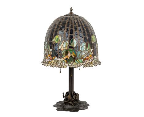  Tischlampe im Stil von TIFFANY'S, 20. Jhd. Brünierter Metallfuß mit Blattdekor, darüber ein glockenförmiger Glaslampenschirm