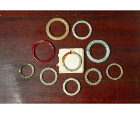A GROUP OF TEN ASSORTED JADE AND HARDSTONE BANGLES Various sizes, mostly of mottled colour, one agate example Largest 8cm dia