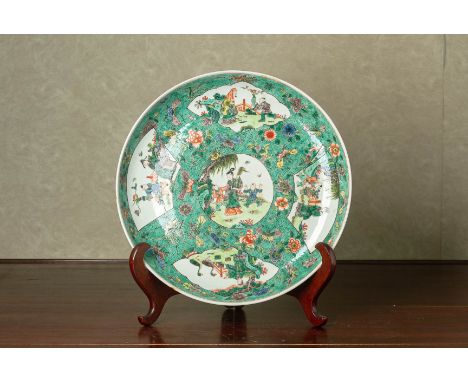 A FAMILLE VERTE PORCELAIN CHARGER Of Kangxi style, painted with reserves of figures at various activities, on a foliate green