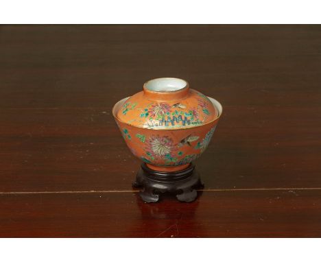 AN ORANGE GROUND FAMILLE ROSE PORCELAIN BOWL AND COVER
Decorated with insects amongst flowering foliage, with later stand 
Ir