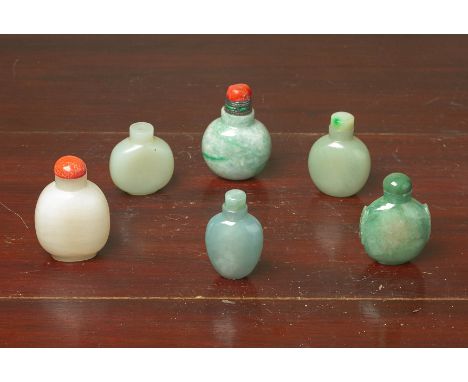 A GROUP OF SIX JADE SNUFF BOTTLES Mostly of plain form, one with twin mask handles, in mottled green and pale celadon colours
