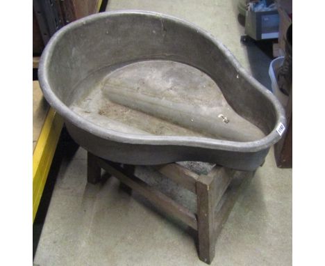 A vintage galvanized saddle shaped basin/planter with central well/channel raised on a wooden stand