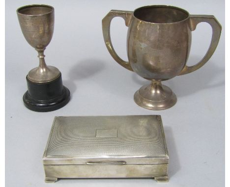 A mixed collection of silver to include a twin handled cup, a further silver pedestal cup and engine turned silver cigarette 