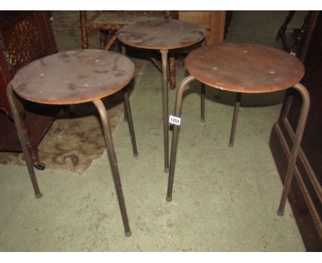 A stack of three mid 20th century low stools with circular laminated seats raised on tubular steel tripod supports, indistinc