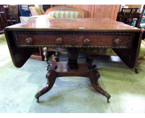 A Regency mahogany sofa table enclosing two real and two dummy drawers with split spindle mouldings raised on a turned pillar