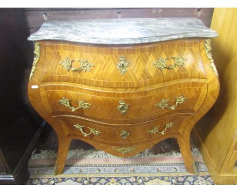 A serpentine commode in the Louis XV style, enclosing three drawers, beneath a shaped marble top, with cast brass fittings, 1