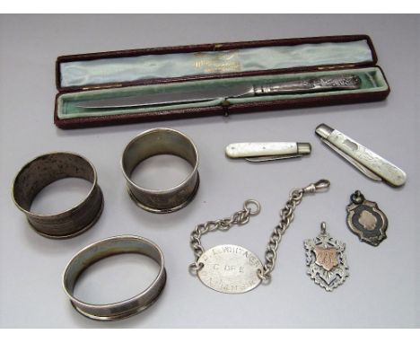 A collection of bijouterie silver to include two folding pearl fruit knives, two silver medals, three napkin rings, further s