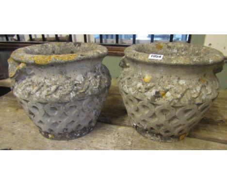 A pair of weathered reconstituted urns with repeating Celtic knot detail 