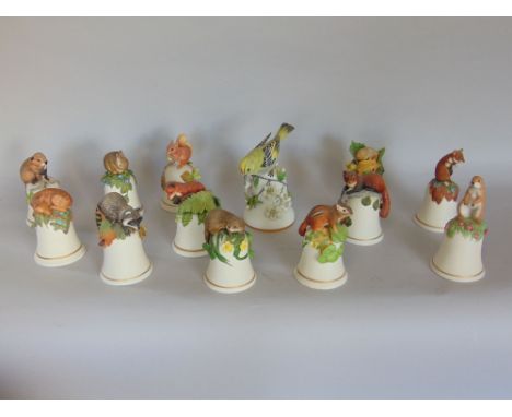 Set of 12 Peter Barrett bisque porcelain bells, each mounted by a wooden creature; together with a further gold crest bisque 