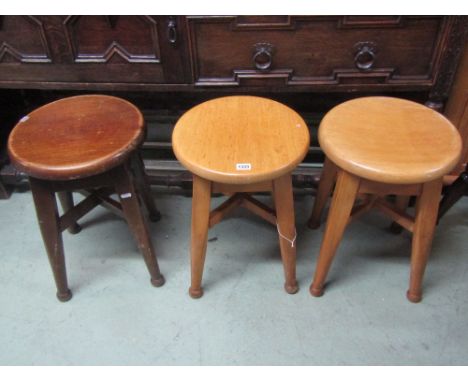 A pair of light beechwood low stools with circular seats raised on square cut and turned tapered supports united by x framed 