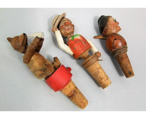 Three Black Forest automaton bottle stoppers, one in the form of a drinking dog, together with a man who raised his cap and m