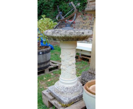 A partially weathered contemporary cast composition stone sun dial with trailing relief fruiting vine detail and raised armil