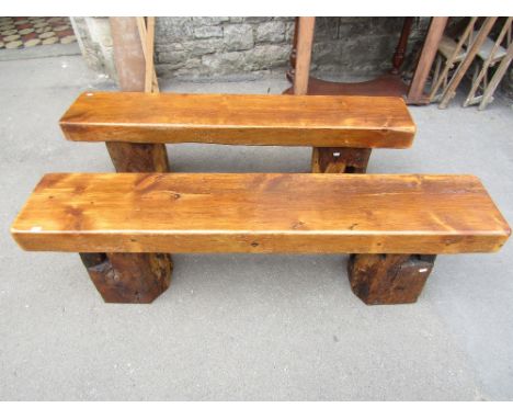 A pair of rustic wooden benches with thick rectangular seats and rustic supports made from reclaimed architectural timbers, a