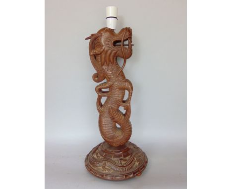 An interesting carved hardwood table lamp in the form of a dragon, with further serpent detail to the circular plateau, 48cm 