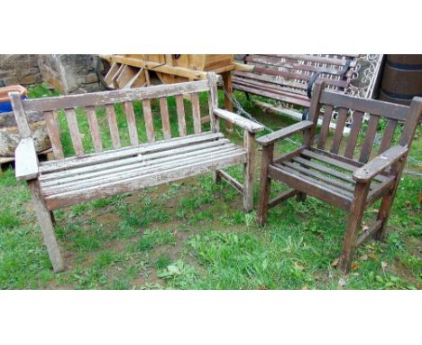 A small weathered teak wood garden bench with stick back and matching single chair