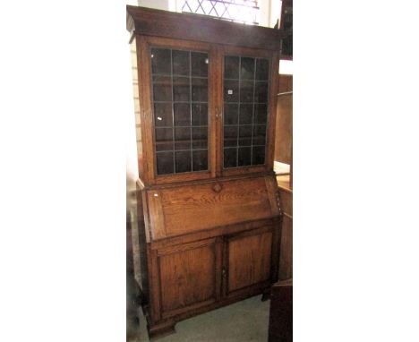 An Edwardian slim oak bureau bookcase, the stepped and moulded cornice with blind fret frieze over a pair of glazed leaded li