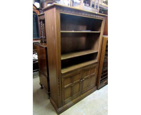 An Ercol Golden Dawn book case with two open shelves over a cupboard enclosed by a pair of quarter panelled and moulded doors