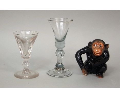 An antique cordial glass, with shaped stem, together with a further cordial glass and ceramic study of a chimp (3)