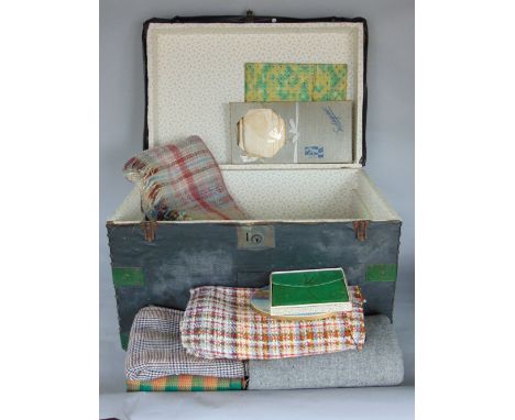 A leather bound studded wooden trunk containing a quantity of tweed remnants, woollen blankets, handkerchiefs and table linen