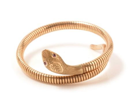 A 9ct gold bangle in the form of a coiled serpent, with ruby set eyes, 21.7g gross.
