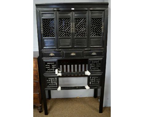 A Chinese ebonised side cabinet, in the antique style, the upper section with a cupboard fitted with fretwork doors enclosing