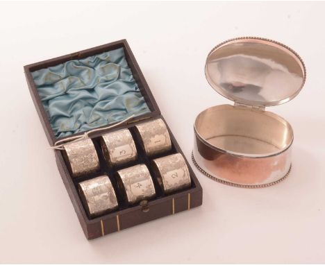 A Victorian cased set of six base metal napkin rings with bright-cut decoration, and an electroplate hinged caddy.