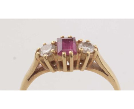 A diamond and ruby three stone ring, on 18ct gold, having a central baguette-cut ruby flanked by a pair of diamonds, each app