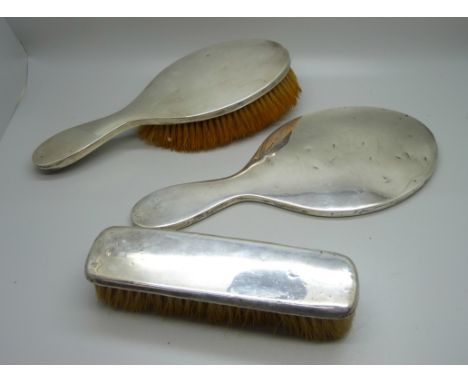 A three piece silver vanity set, hand mirror and two brushes 