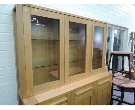 A modern golden oak lounge unit, having glazed display shelves, frieze drawers and triple cupboard under, retailed by Marks a
