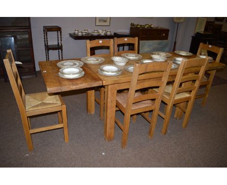 A rustic oak draw leaf dining table fitted single frieze drawer; together with six ladder back dining chairs with rush seats.