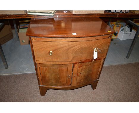 An early 19th Century and later bowfront commode cabinet, fitted a drawer and two cupboard doors, 64cms wide.