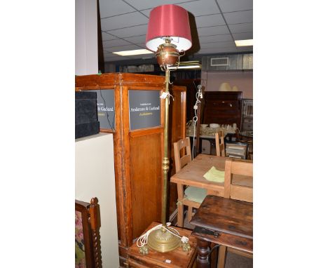 A Victorian brass and copper standard lamp (converted to electricity), raised on a turned column on circular base with paw fe