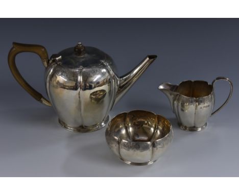 A late George V silver three piece lobed ovoid tea service, comprising teapot, milk jug and sugar bowl, each lightly engraved