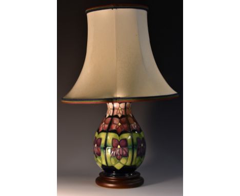 A contemporary Moorcroft Violet pattern baluster table lamp, tube lined with stylised flowers, in tones of purple on a green 