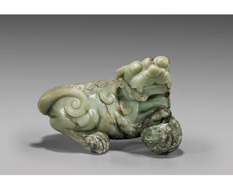 MASSIVE CARVED JADE FO LIONMassive and heavy, Chinese carved celadon jade model of a Fo lion; the recumbent animal with a bal