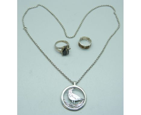 A silver bird pendant and two silver rings, N and R 