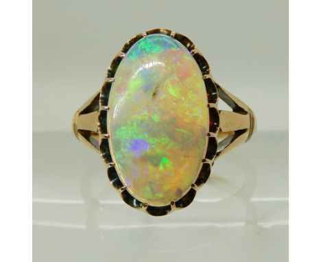 AN 18CT GOLD OPAL RING in scalloped galleried mount, with fleur de lis shoulders. Dimensions of the opal 15mm x 8.9mm x 2.6mm