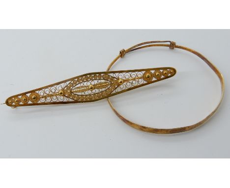 A CHINESE GOLD CHILD'S BANGLE AND A YELLOW METAL FILIGREE BROOCH the bangle expands to maximum 5.5cm diameter, width at wides