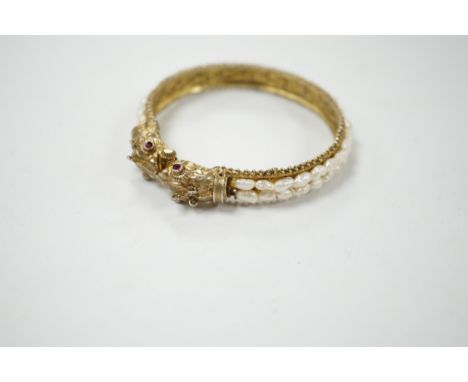 A Chinese? gilt white metal and freshwater pearl cluster set hinged bangle, with red stone eyes. Condition - fair