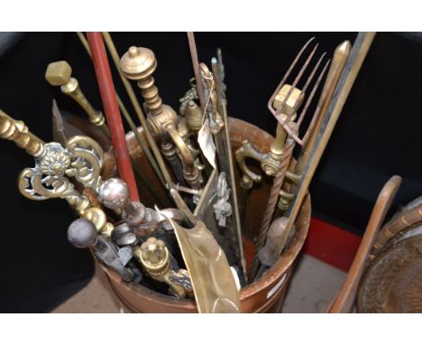A large collection of brass and copper fireside compendiums held within a vintage barrel

