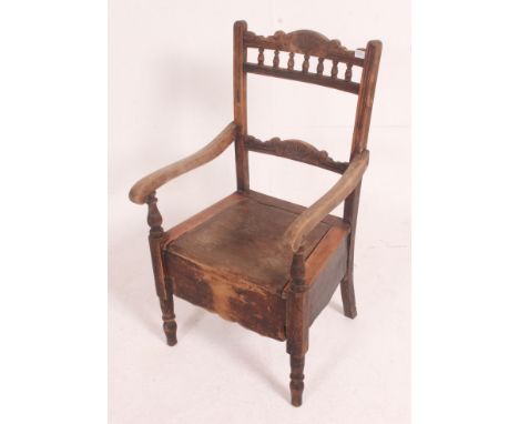 A  Victorian commode chair in oak being raised on turned legs having a hinged seat with decorative carving.elsewhere  Measure