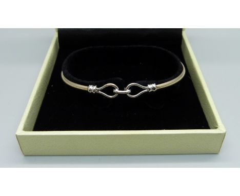 A yellow and white metal bangle, 8.5g, tests as 9ct gold 
