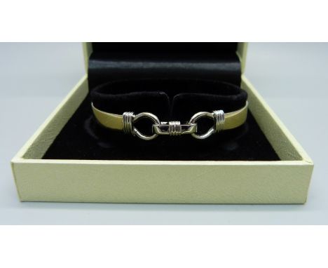 A yellow and white metal bangle, 16.6g, tests as 9ct gold 