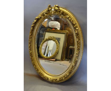 An Oval Gilded Wall Mirror with Ribbon Bow Cresting, 86 x 65 cms