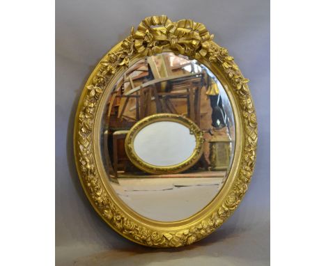 An Oval Gilded Wall Mirror with Ribbon Bow Cresting, 73 x 60 cms