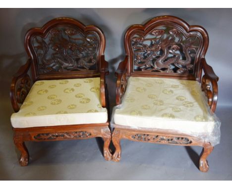 A Pair of Chinese Hardwood Armchairs, each with a pierced carved back depicting a serpent above a panel seat with loose cushi